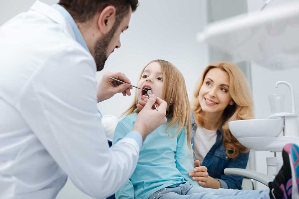 A dental hygienist cleaning an adult patient's teeth in a bright, modern clinic.