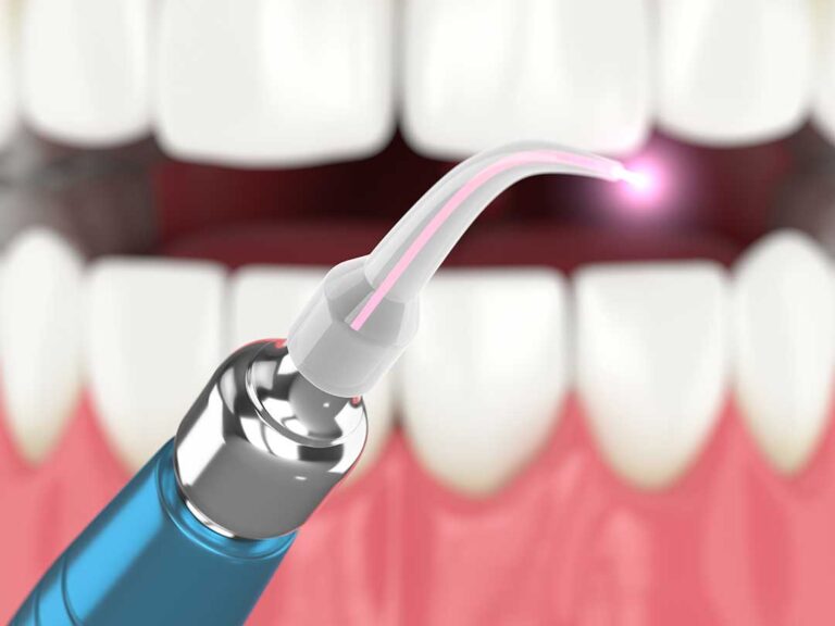 Person gently guiding floss in a C-shape around a tooth at a bathroom sink.